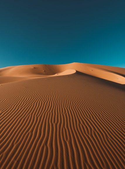 Vertical shot of a peaceful desert under the clear blue sky captured in Morocco A vertical shot of a peaceful desert under the clear blue sky captured in Morocco